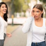 Happy girl greeting waving hand and friend ignoring her